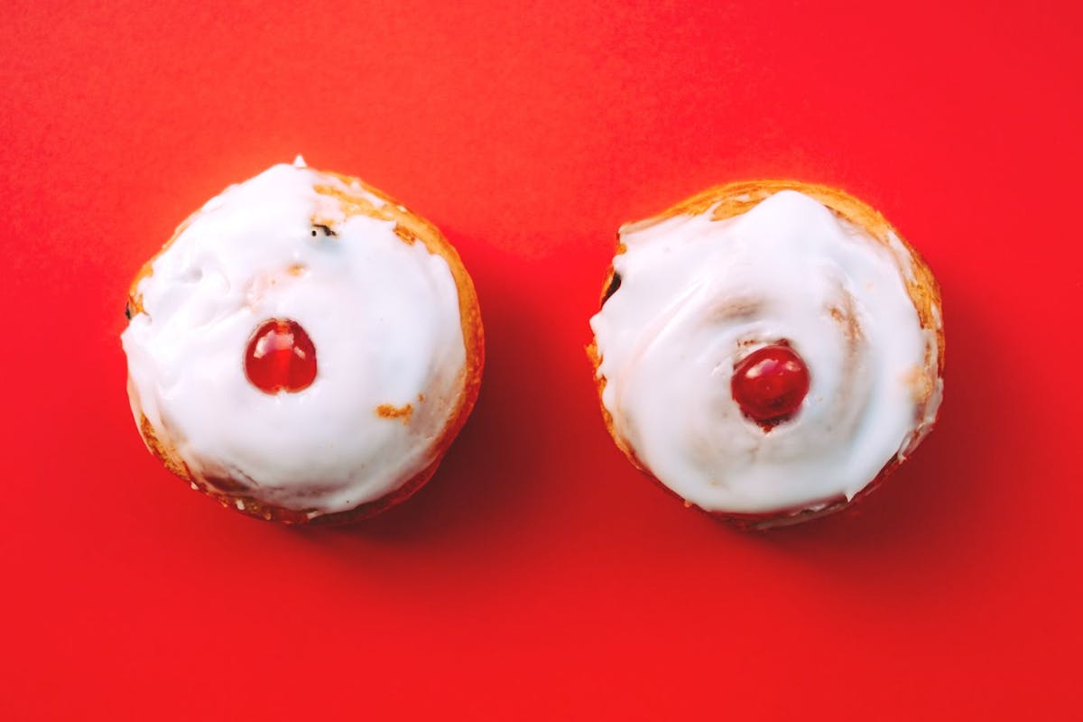 A photograph of two iced cherry buns on a red background