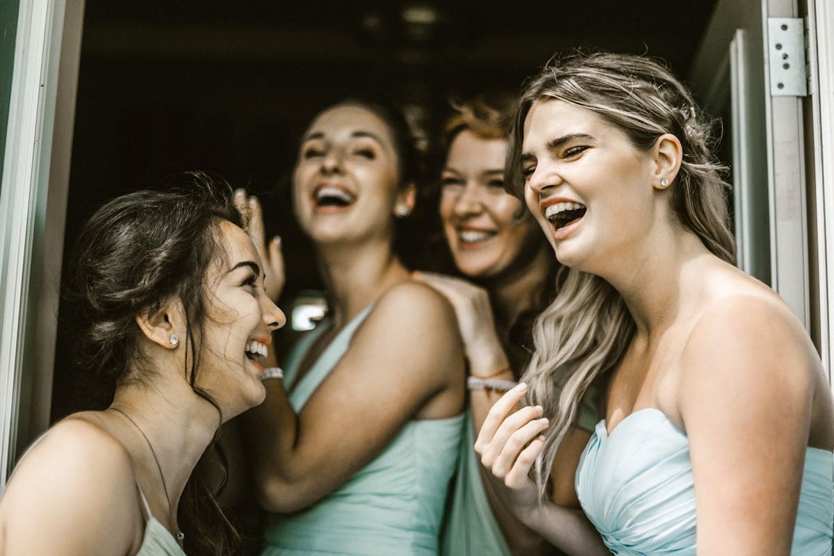 A bride and her bridesmaids share a laugh before the wedding
