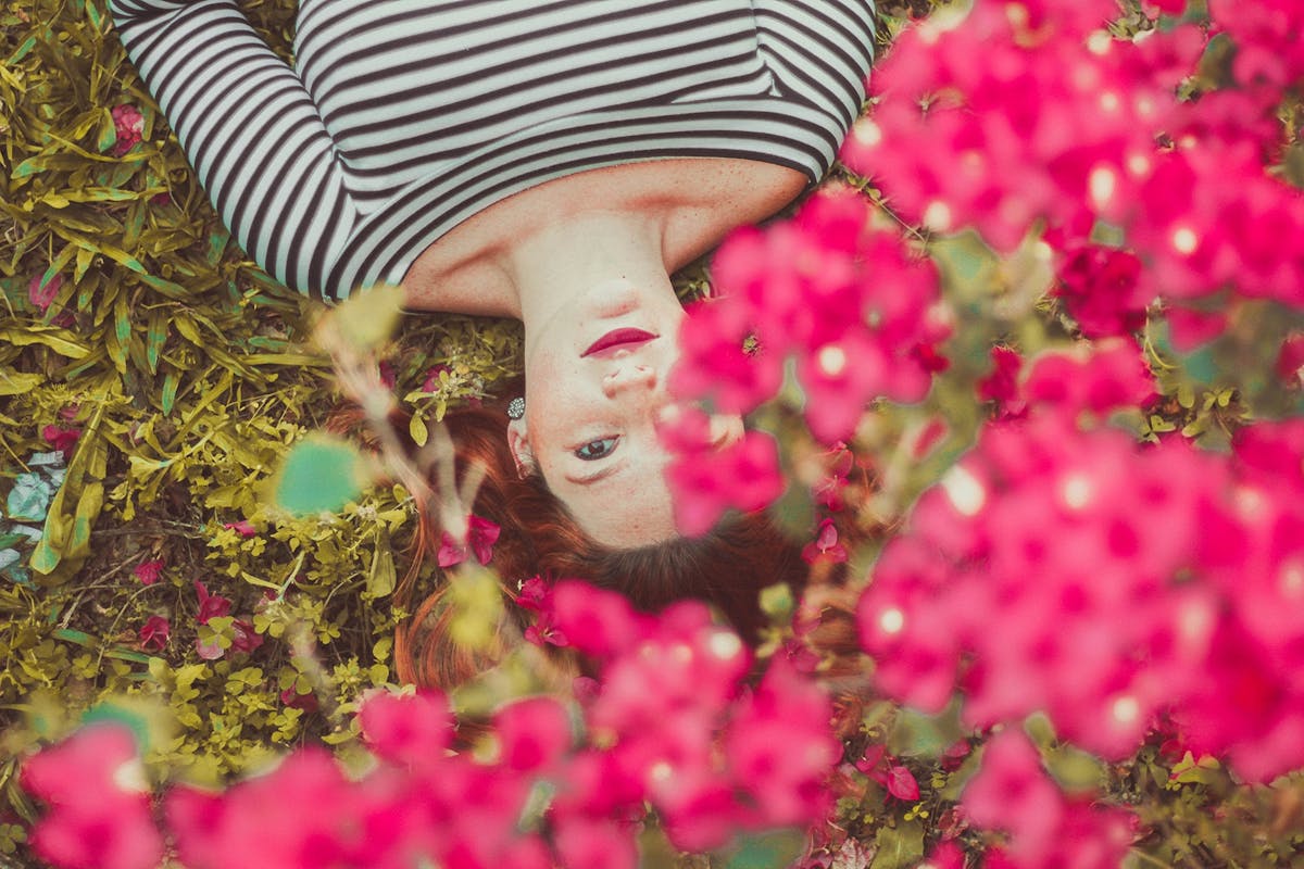 Woman lying in grass under flowering tree