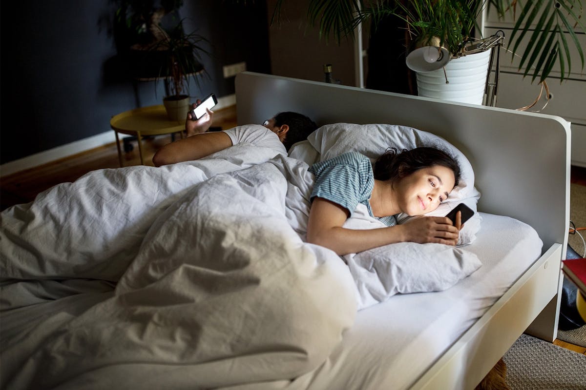 A couple in bed using their phones