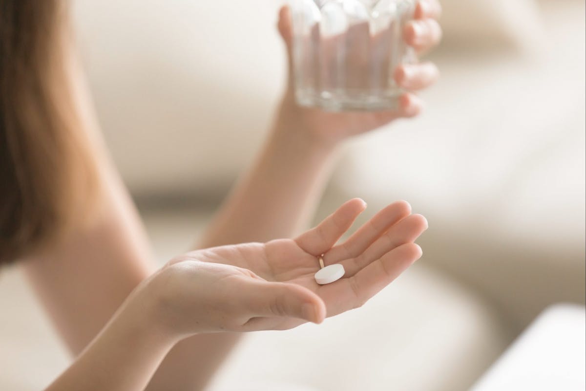 woman holding anti depressant pill in her hand and water