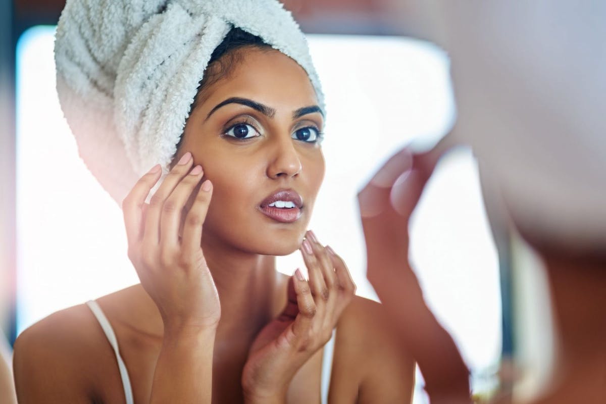 Woman applying skincare in mirror