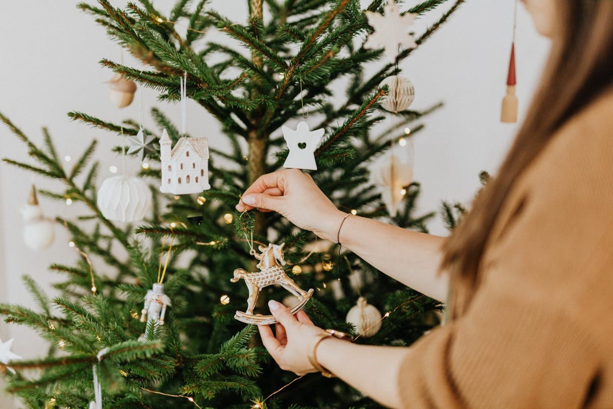 A woman hanging a decoration on the tree