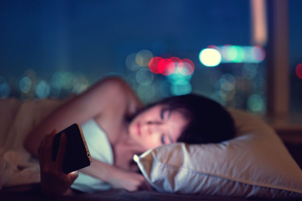 A woman reading her phone in bed