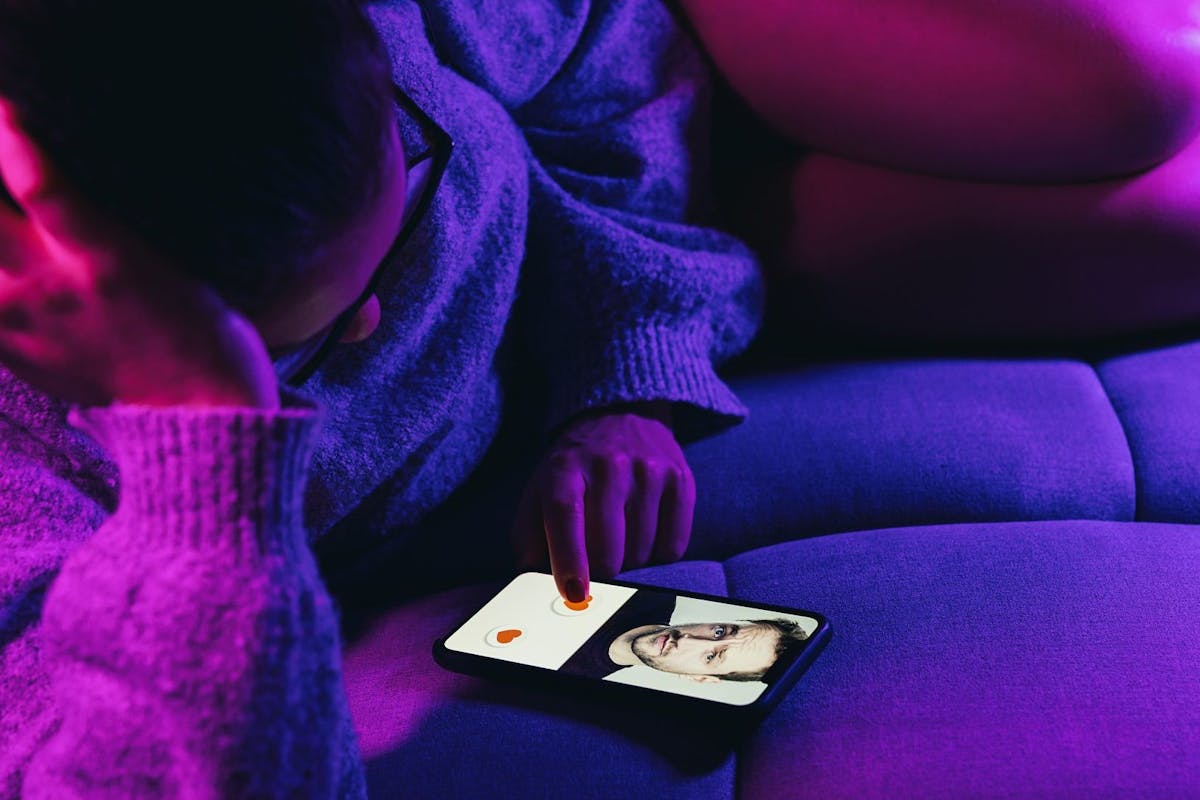 Woman lies on sofa swiping and liking profiles on dating app