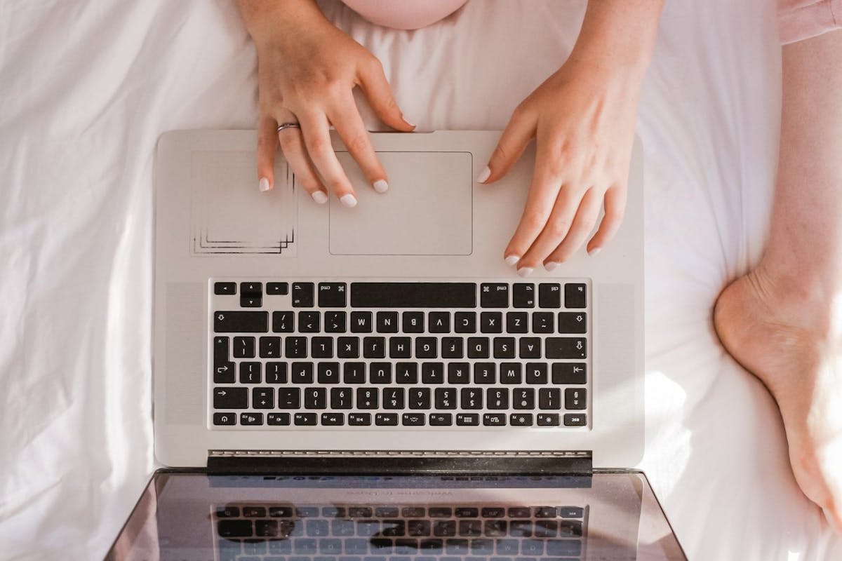 Woman sat with her laptop in bed
