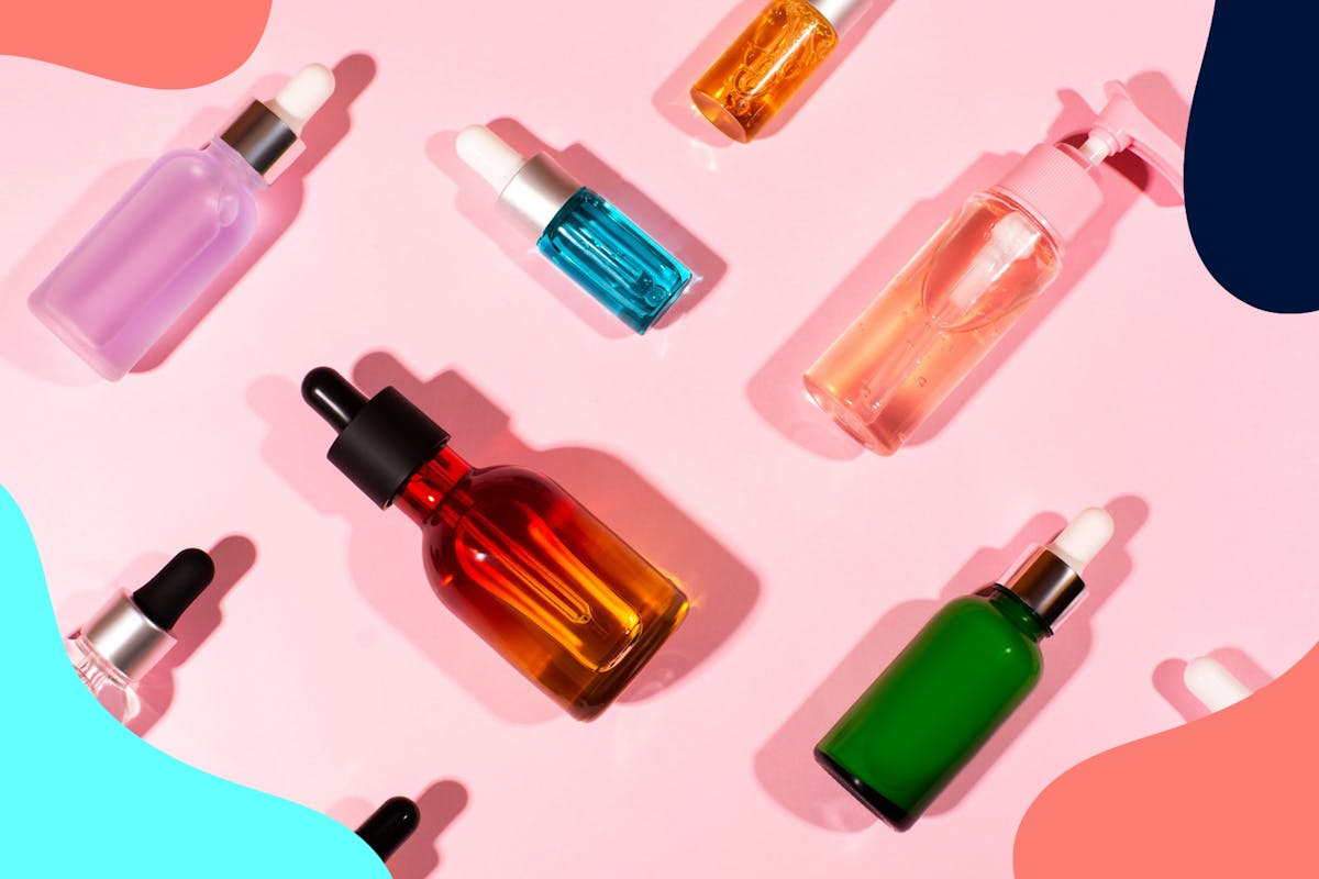 beauty product bottles scattered on pink background