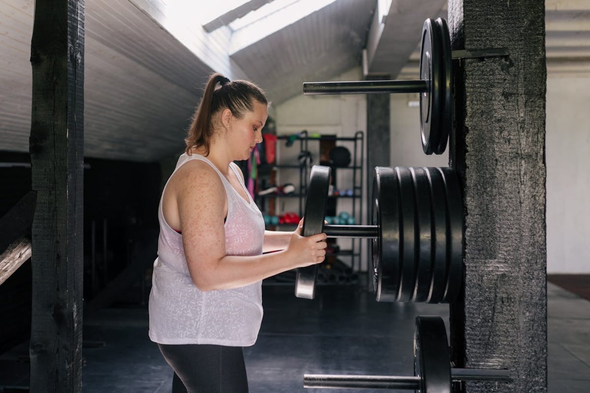 A woman loading up a barbell with weights.