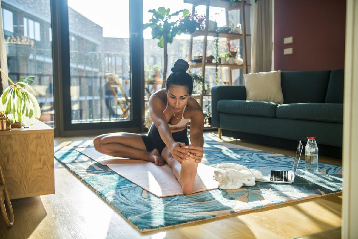 Woman stretching on yoga mat at home