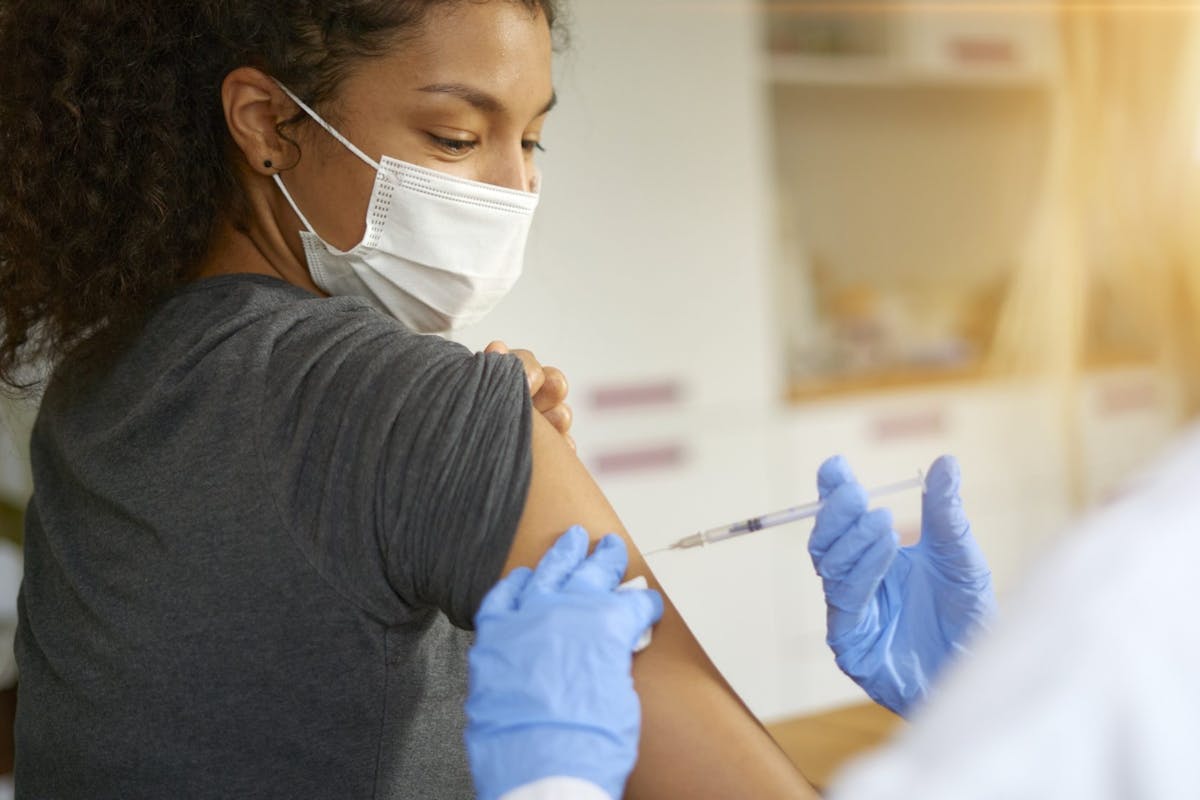 Young woman wearing a mask being vaccinated