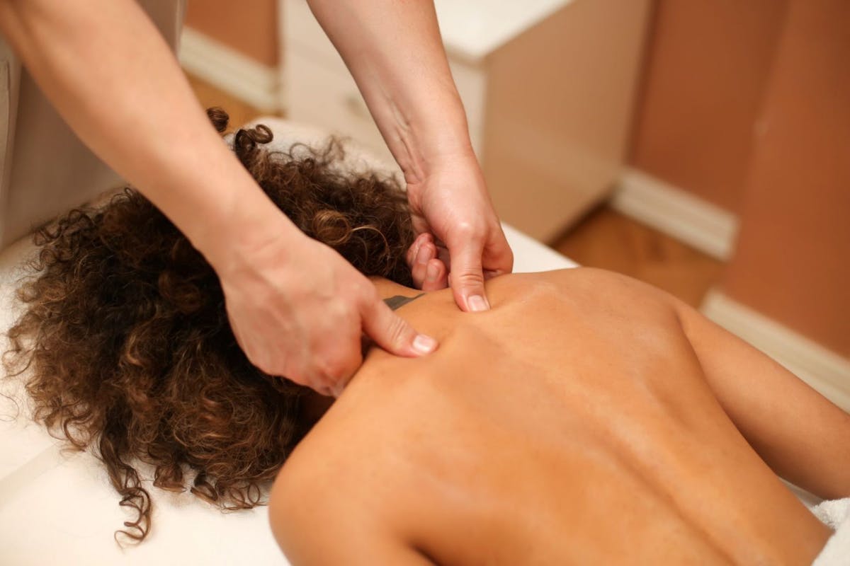 A woman face down on a massage table having her back massaged.