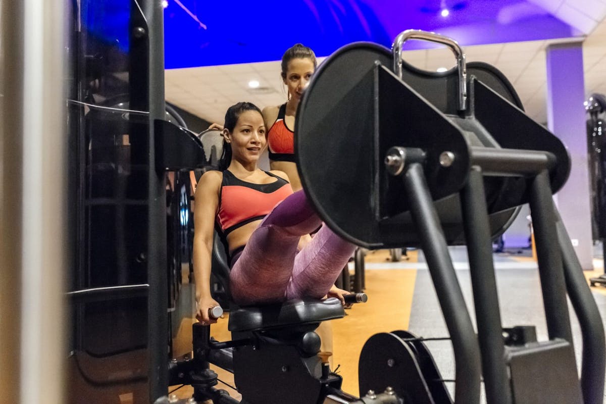 A woman on a leg press machine with a personal trainer