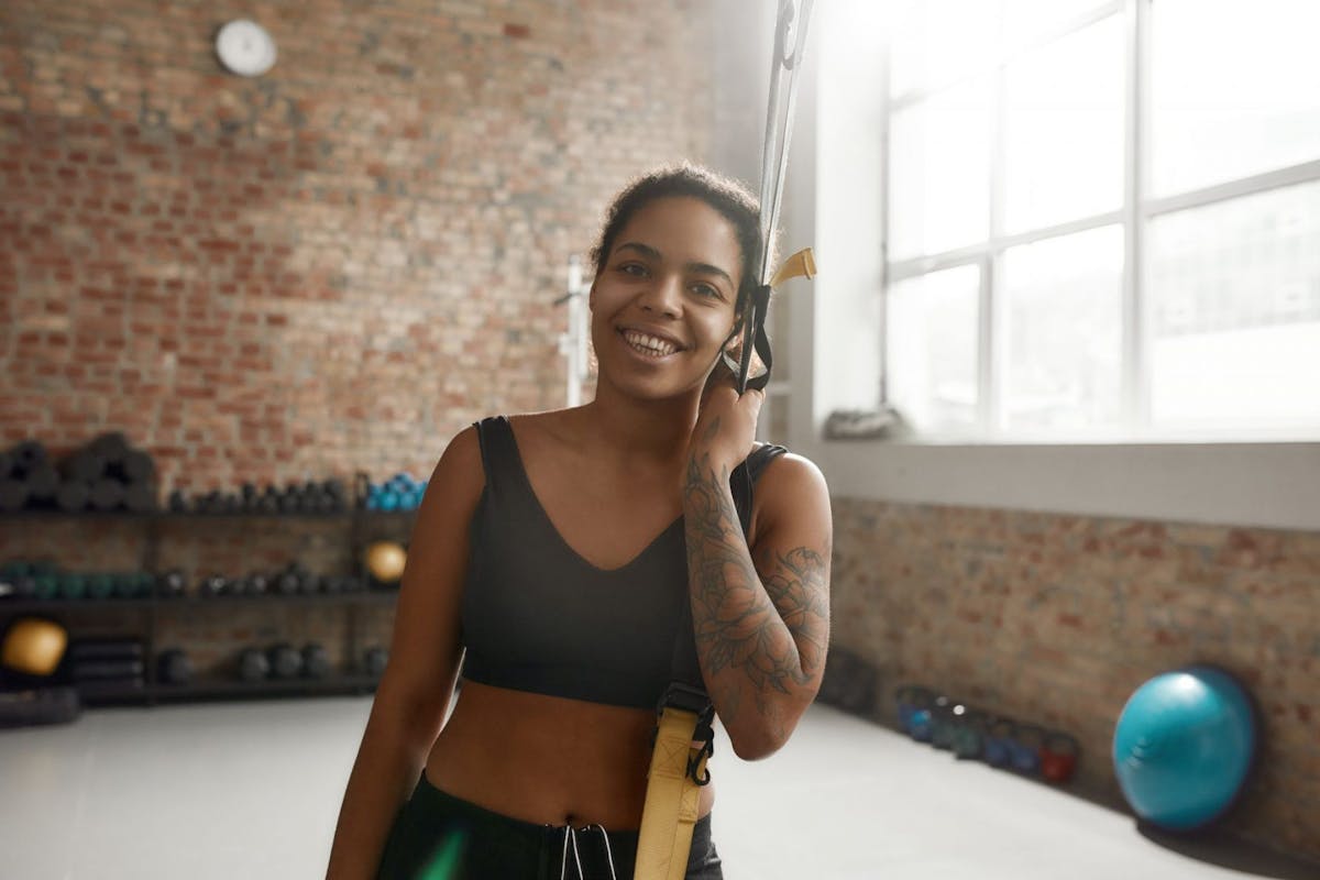 A woman smiling in the gym with a TRX