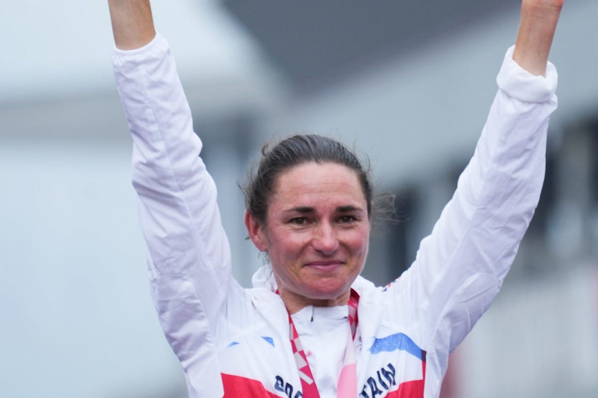 Sarah Storey on the podium with a gold medal around her neck and flowers in her hands