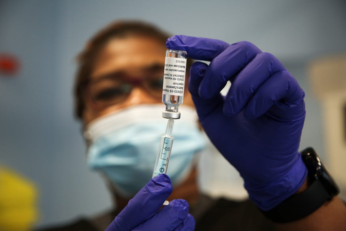A woman withdrawing vaccine from a vial
