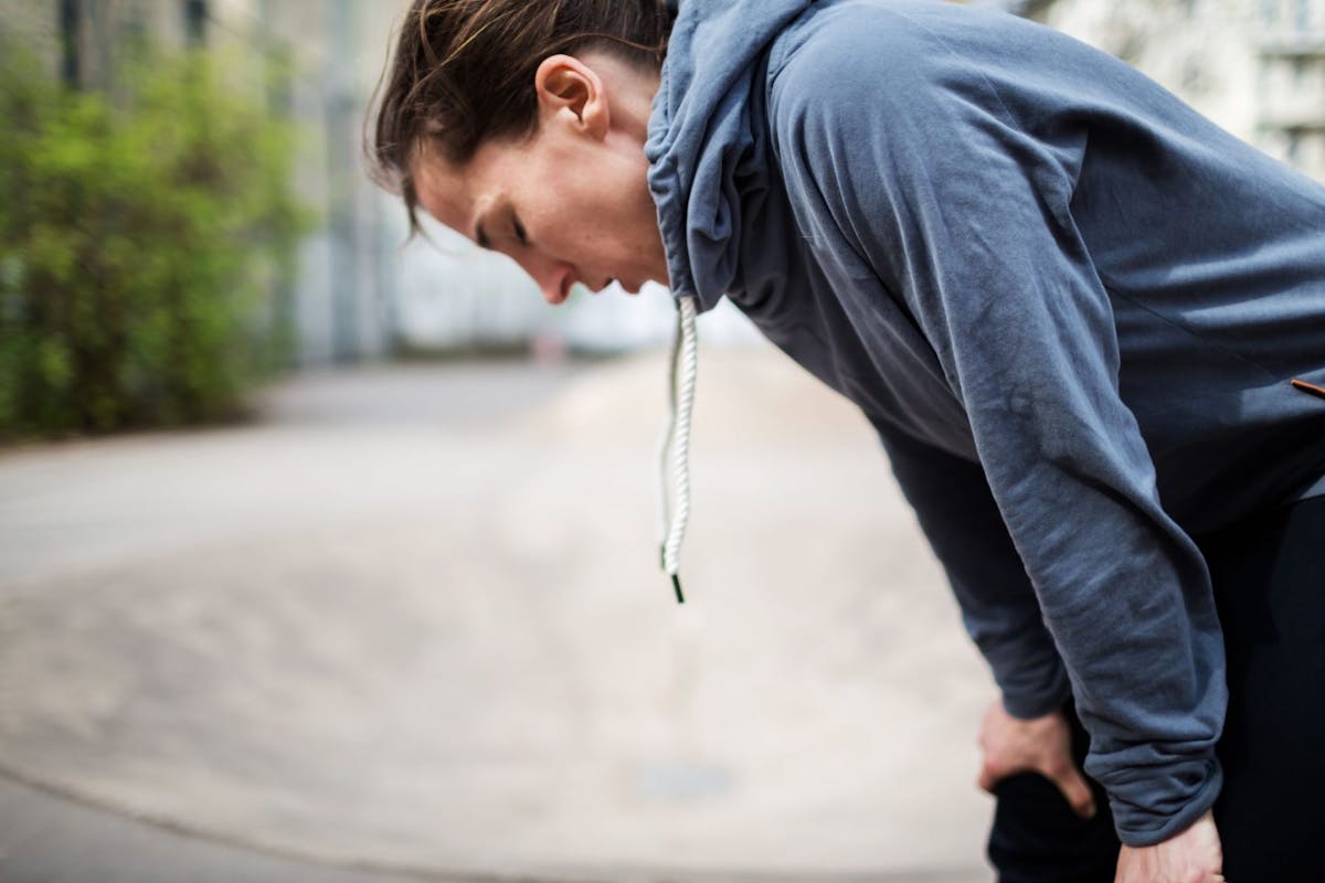 A woman bent over feeling unwell after exercise