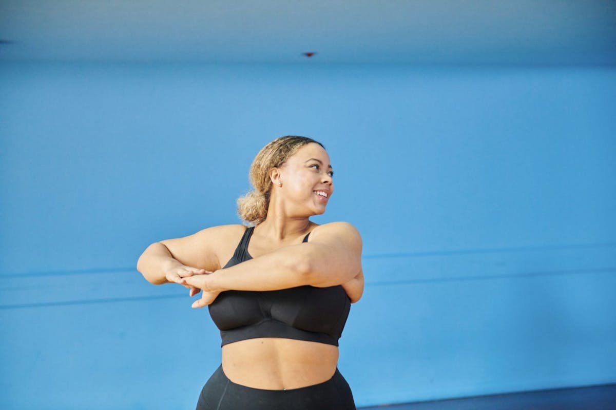 A woman smiling while stretching at the gym