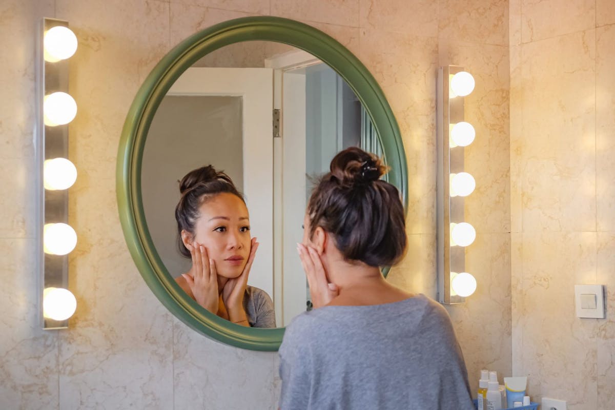 Woman looking at her skin in the mirror