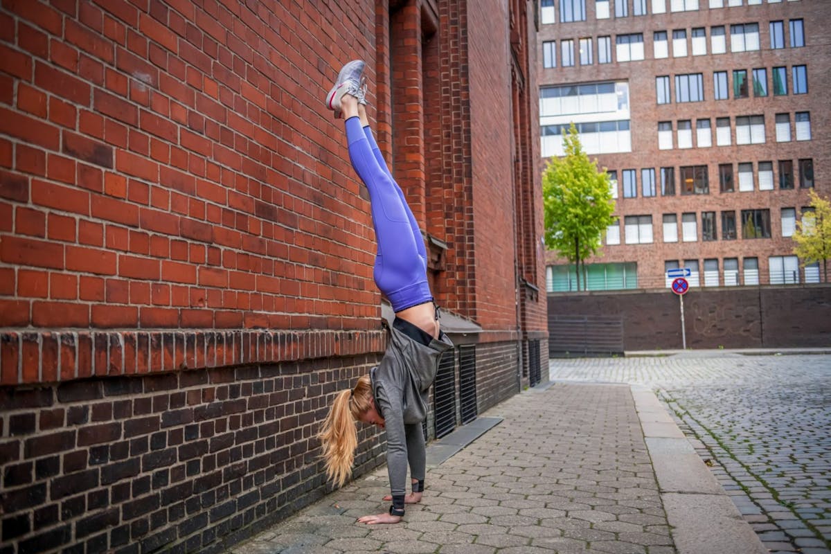 A woman doing a handstand against a brick wall