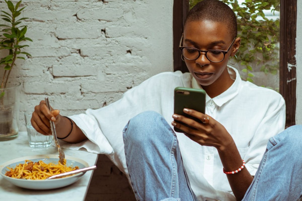 A woman on texting on her phone while eating dinner