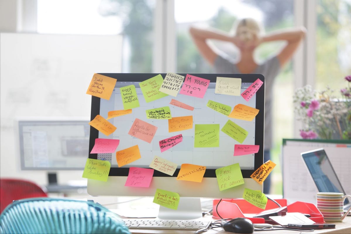 Computer monitor covered in post-it notes due to too much work expected of employee