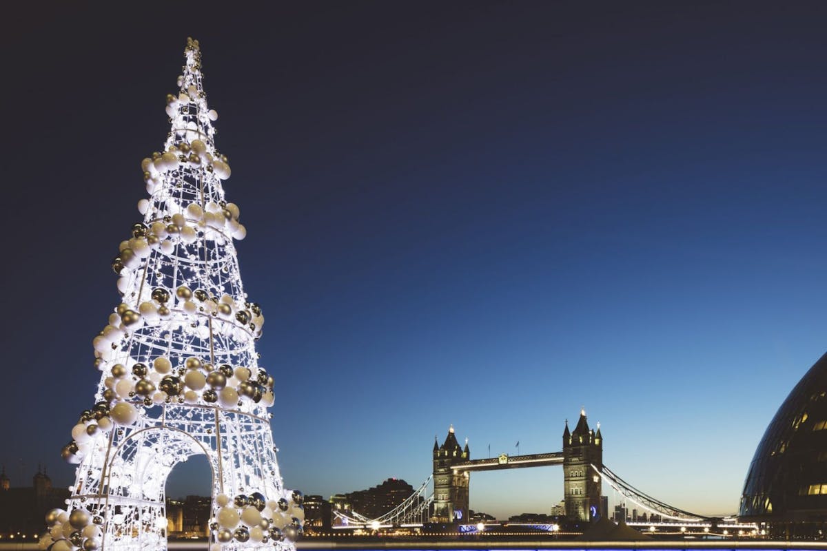 a photo of the UK, London, Tower Bridge at twilight with illuminated Christmas tree in the foreground