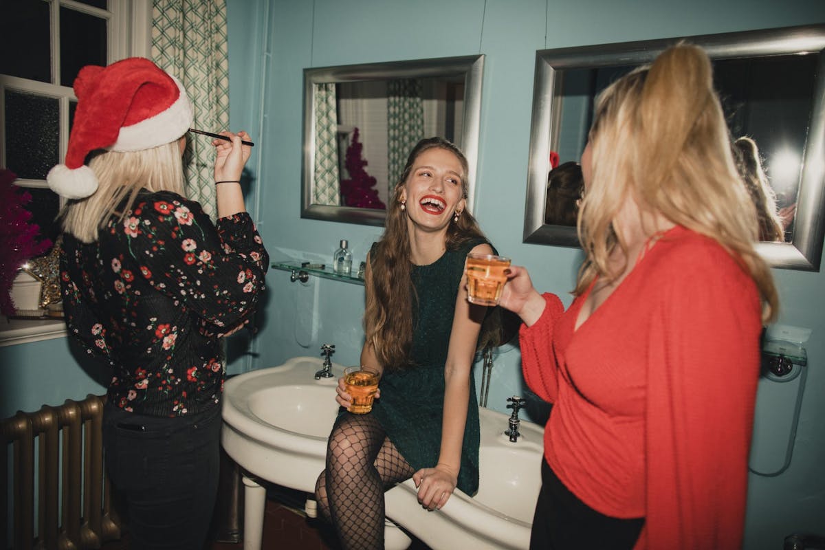 Three women having a drink in the bathroom at a Christmas party