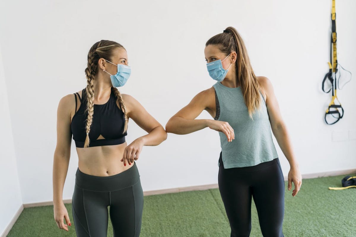 Two women exercising in a gym in facemasks
