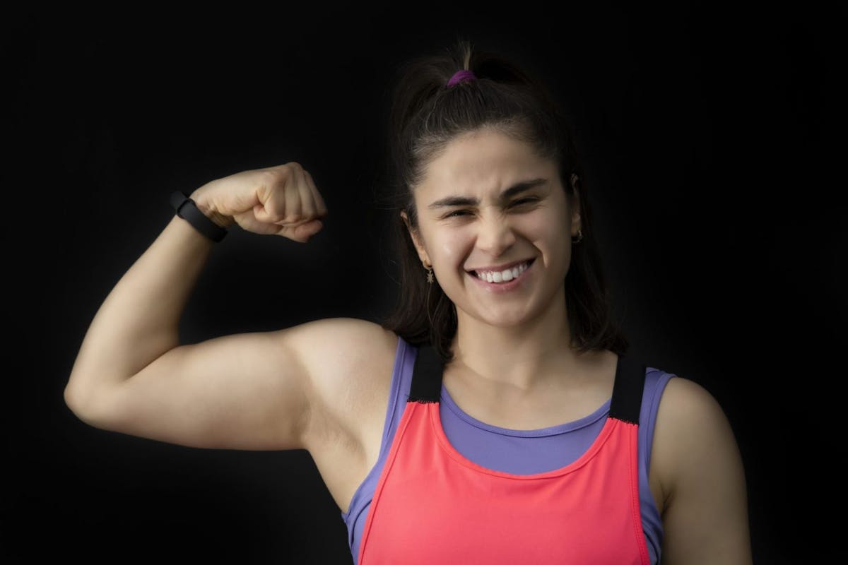 A woman doing a strong pose with her bicep