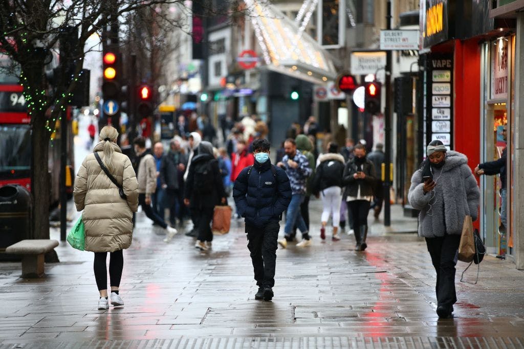 Shoppers, some wearing a facemask to combat the spread of Covid-19, walk along Oxford Street