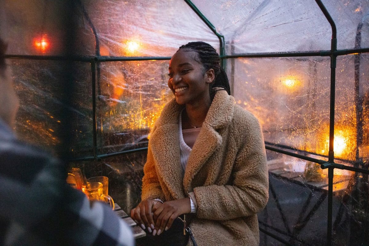 African woman wearing warm coat sitting at cafe with a friend