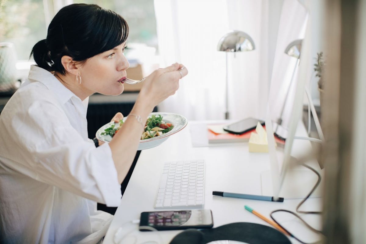 A woman eating a salad at her desk