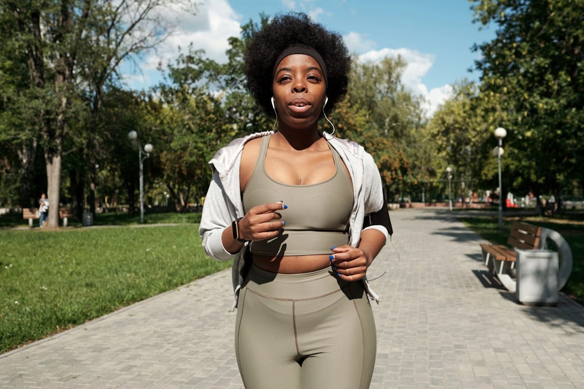A woman jogging through a park in green sportwear