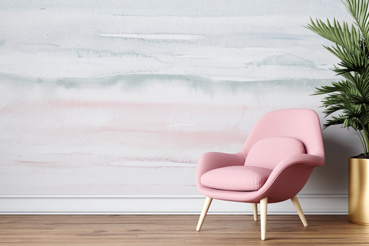 A colour gradient feature wall, with grey, blue and pink tones. In front is a light pink armchair next to a palm in a gold plant pot. Gradient homewares are one of Etsy's interior trends for 2022