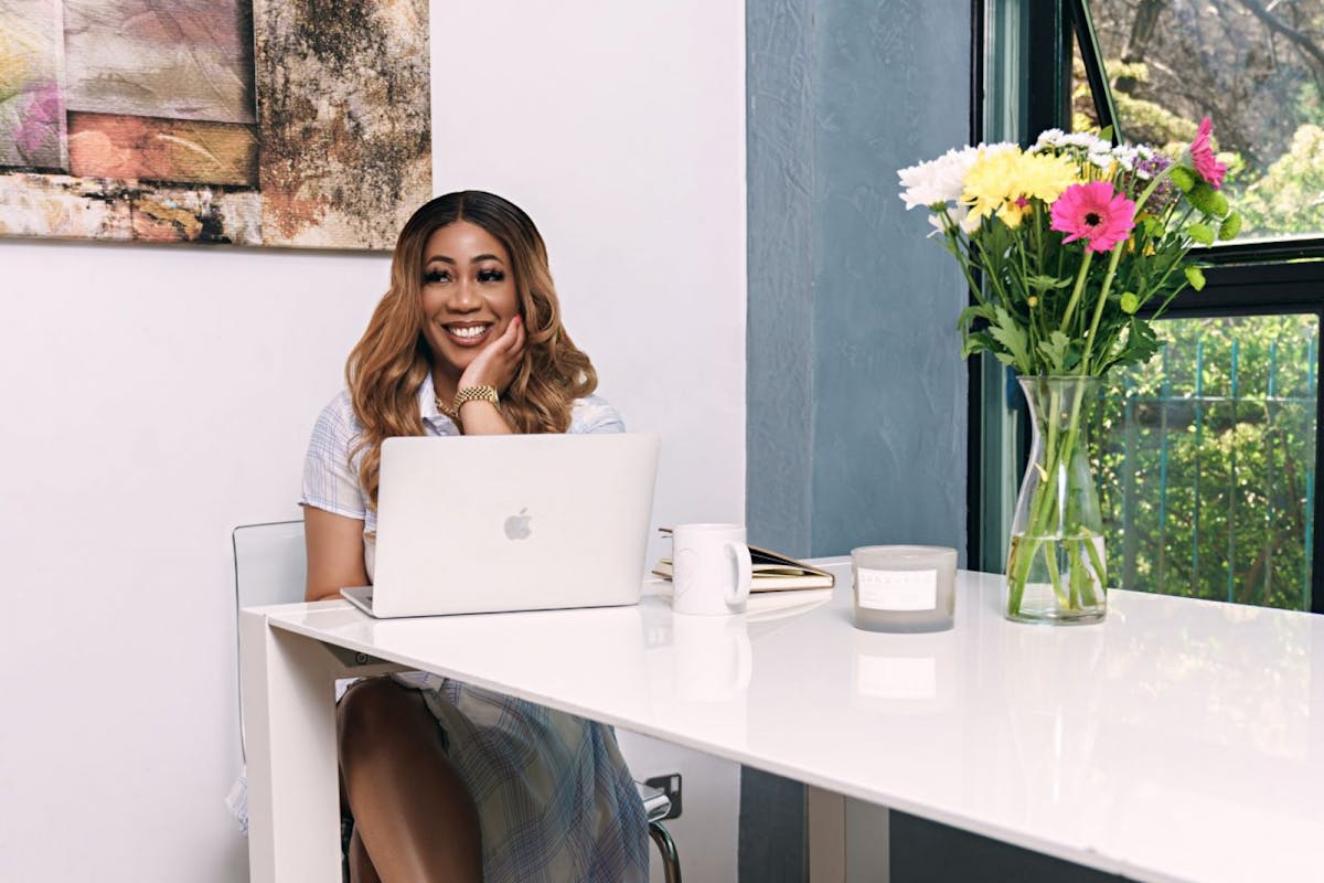 Girls Talk London CEO sits at a work desk with laptop: explains how she helps women to succeed in the workplace