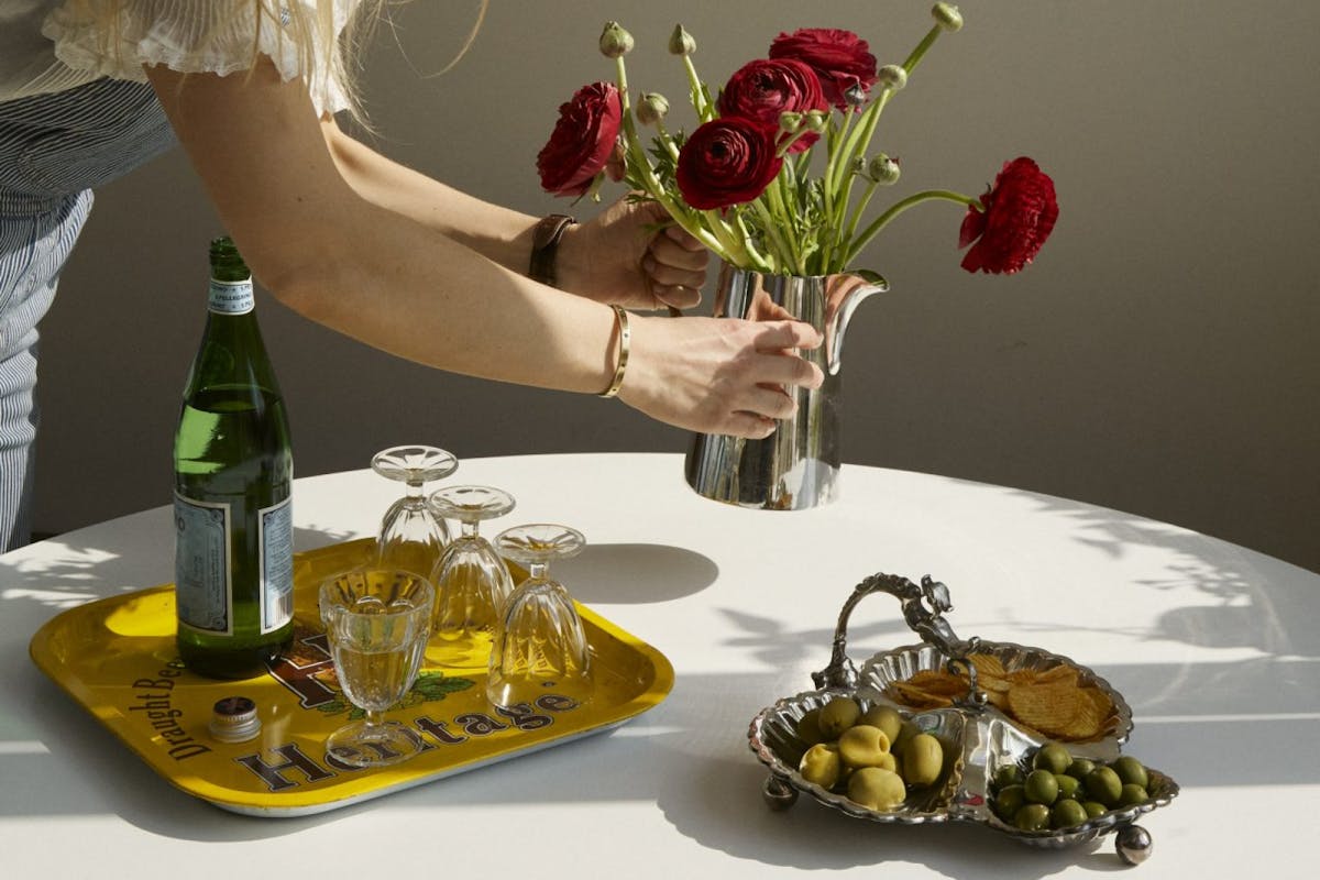 Designer Matilda Goad styles Oxfam homeware items including a silver jug with red flowers and a silver platter with snacks