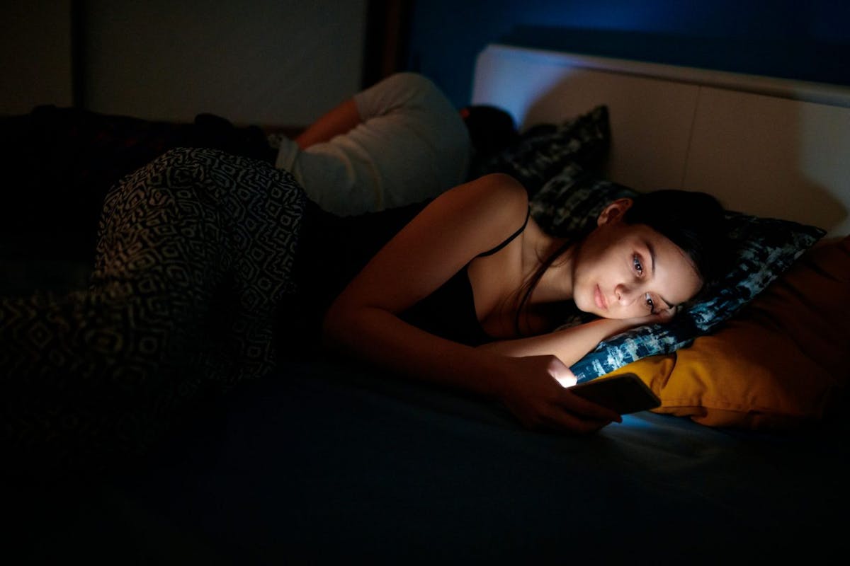 Women looking at phone in bed at night