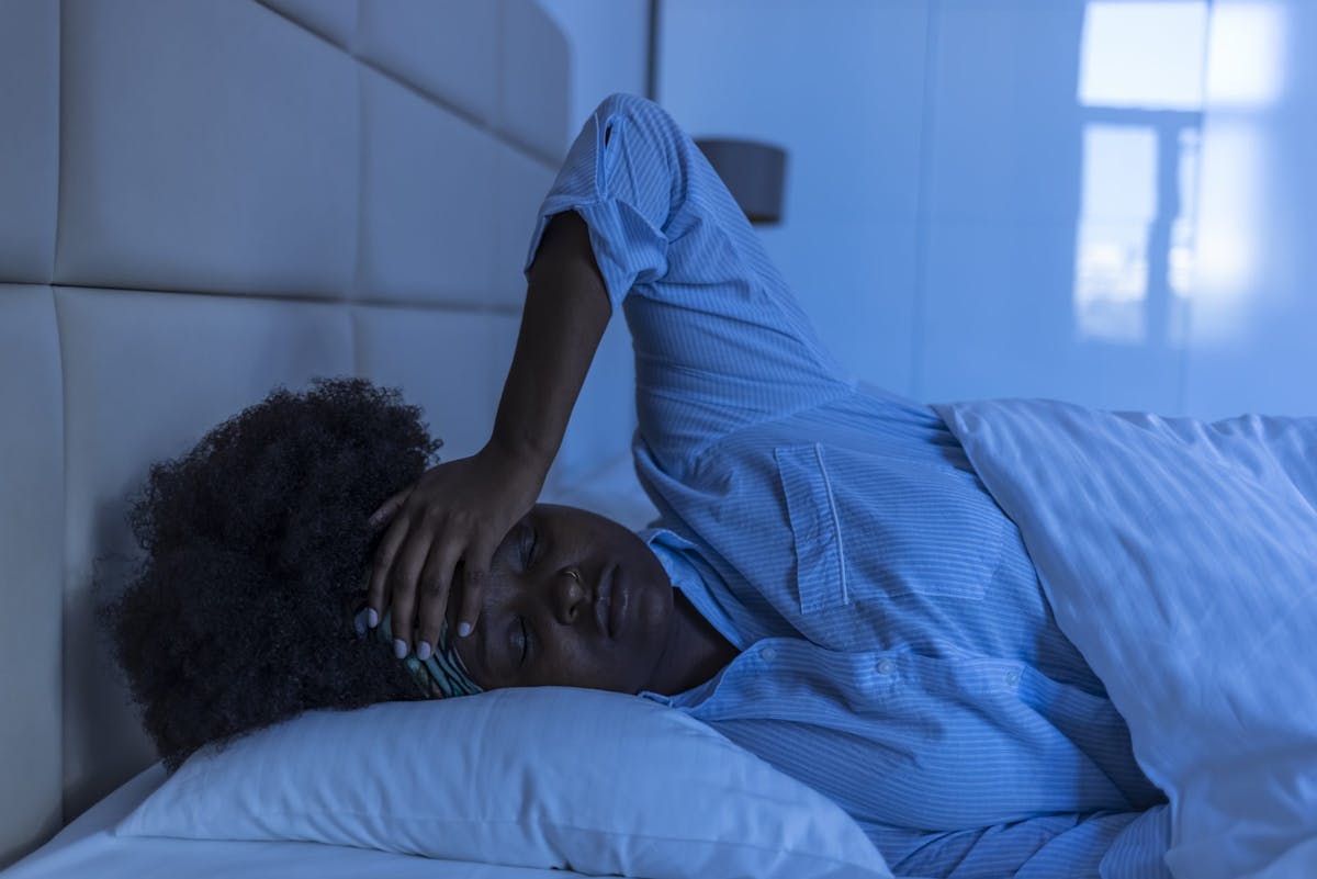 A woman struggling to sleep, lying awake in bed